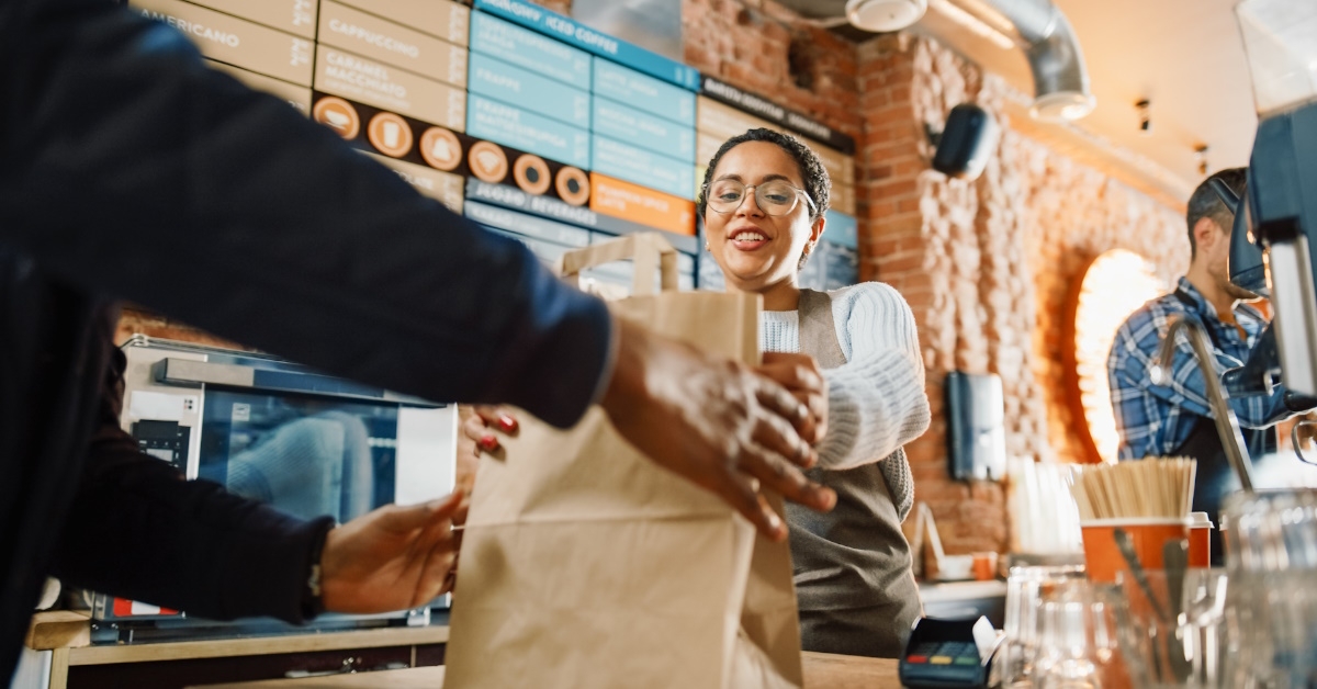 female waitress in cafe serving package to male client 