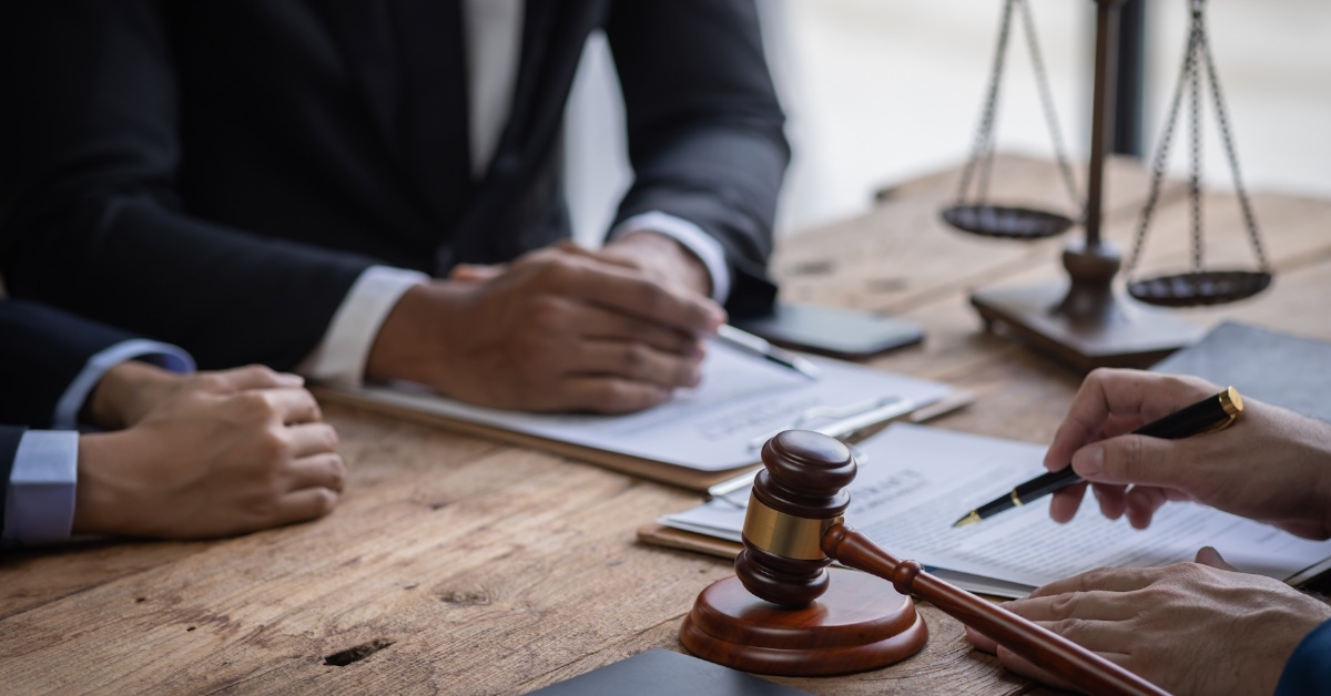 legal advisors sitting at table having documents and papers along with client in court