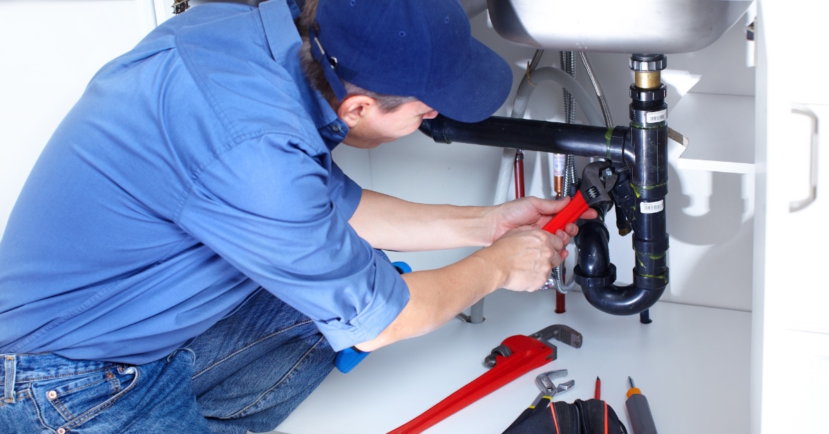 plumber fixing sink in kitchen