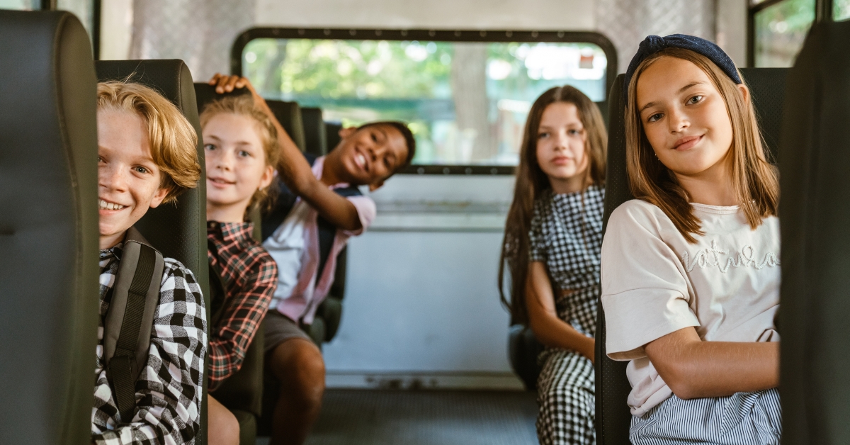 multiracial pupils smiling together in school bus
