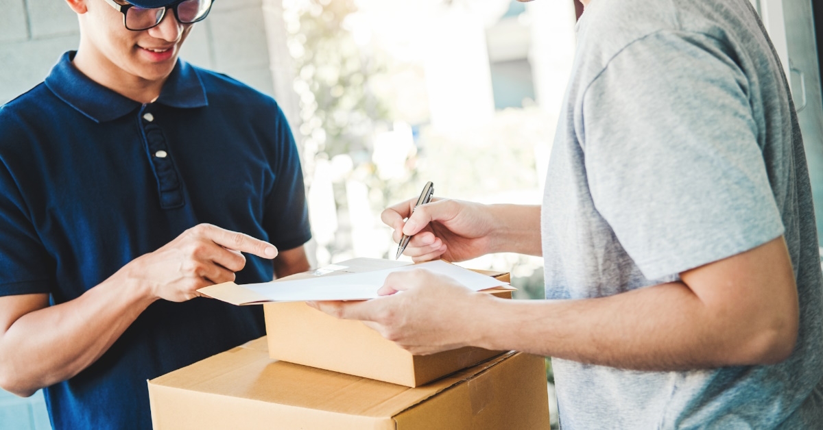Male customer making signature on the clipboard after recieving package from delivery man at home.