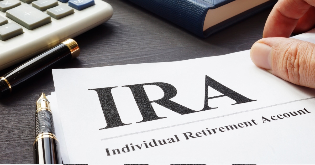 Documents about Individual retirement account IRA on a desk with an opened pen,calculator and a notebook.
