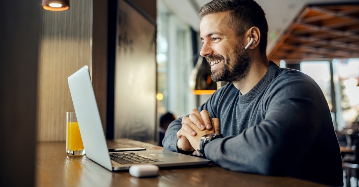 A friendly freelancer is sitting in a cafe and having conference call with client.