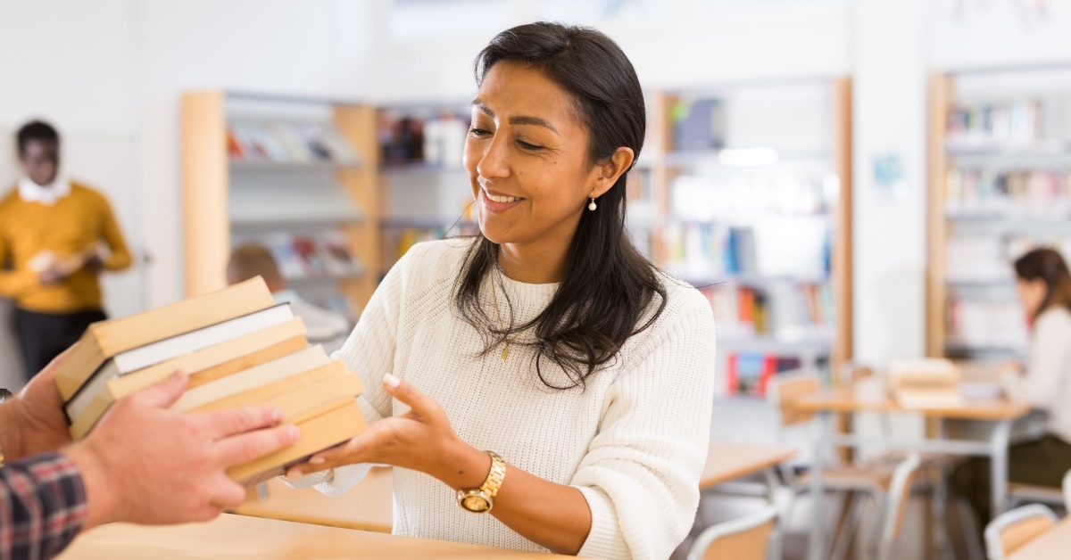 young adult woman returning books to librarian at public library after reading them