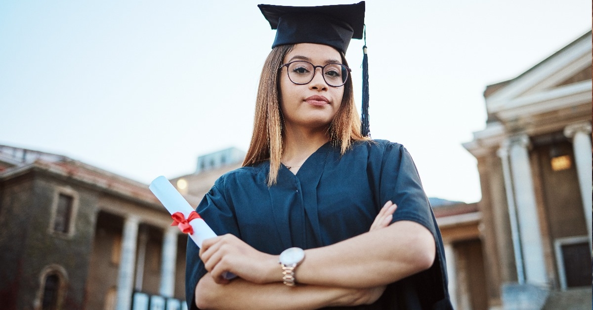Female student wearing graduation dress is holding her degree during graduation cermony at college.