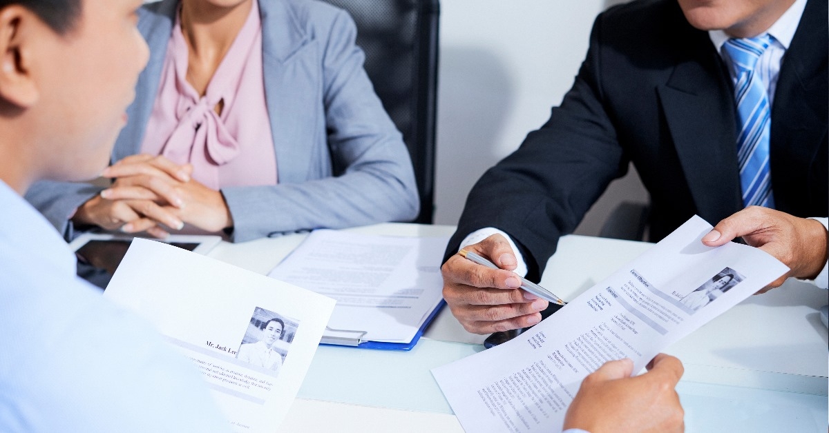 male and female recruiters talking to male candidate while pointing at resume