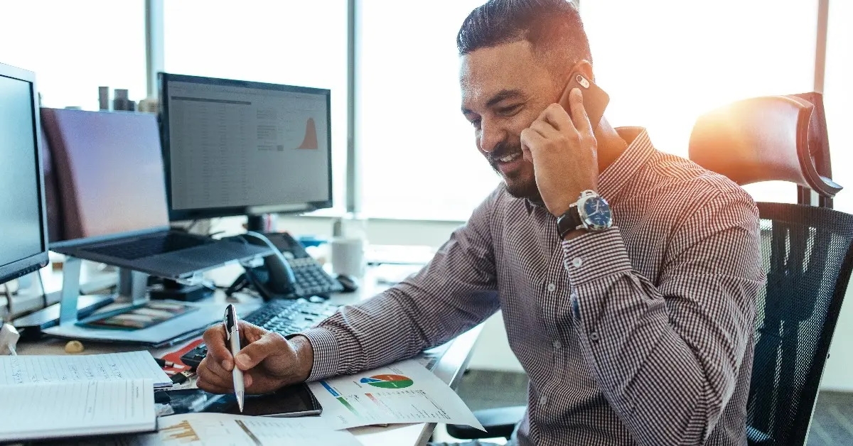 economist analysing statistical data of different parameters and discussing with other colleague at phone call while sitting in office