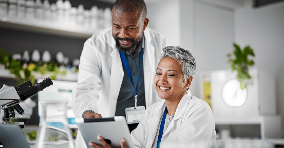 Scientists holding tablets discussing green plant sustainability for growth innovation in a botany lab.