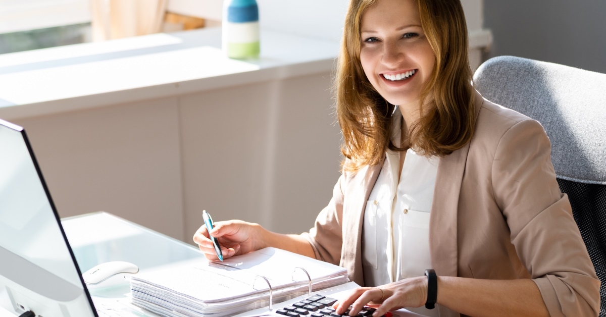 female accountant working in her office on accounting tasks with calculator and notepad.