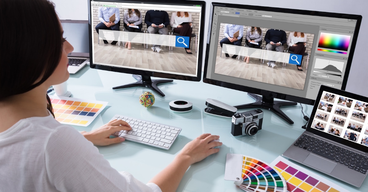 A woman working as a web designer is utilizing multiple computers for her tasks