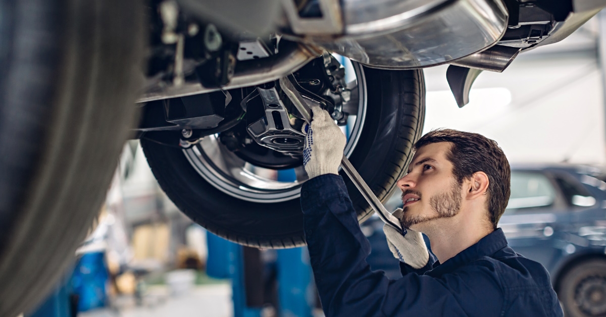 A mechanic at a car repair service center examines shock-absorbing components such as springs and dampers