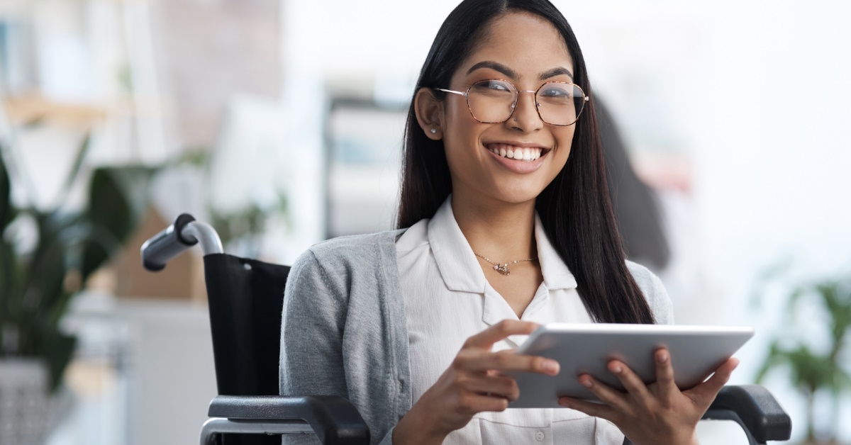 A female website designer in a wheelchair is all smiles while using technology to analyze web and software.