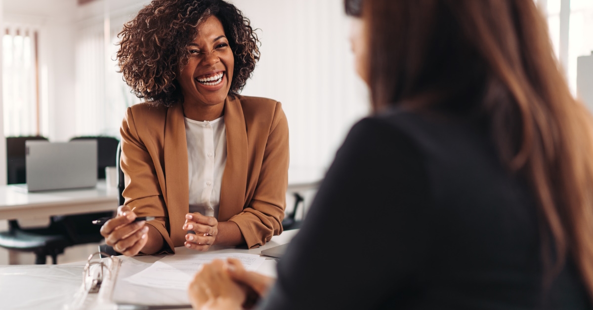 a female financial advisor with short curly hair is consulting a client with joy in her office setting.