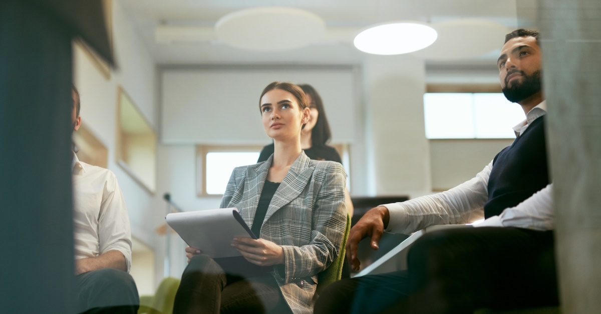  People intently listening and jotting down notes during a business training session held in an office.