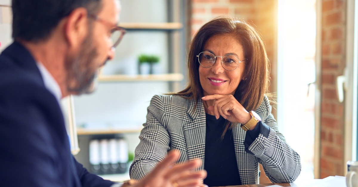 Two middle-aged business workers working together at the office, with happy and confident expressions on their faces.
