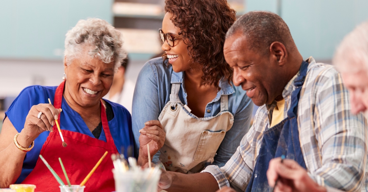 A group of retired seniors who are attending an art class in a community center with a teacher during their leisure time.