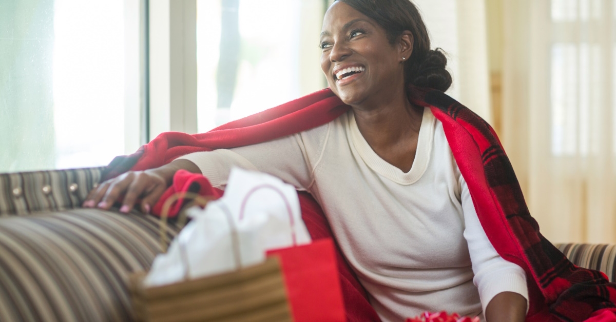 african american woman sitting on couch smiling while celebrating holidays at home