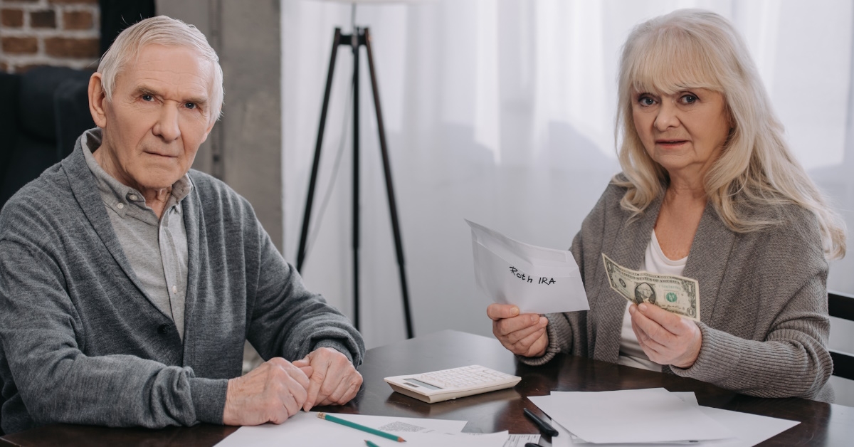 senior couple in shock while checking bills at table and holding money in hand at home