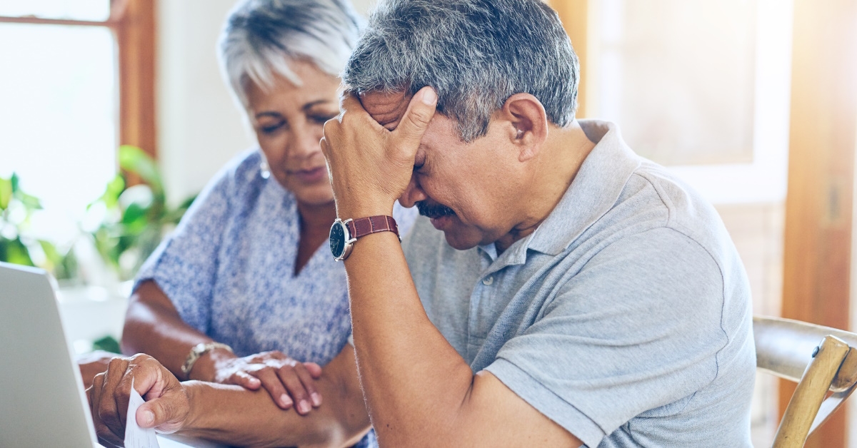 senior couple sitting at table using laptop to read policies 