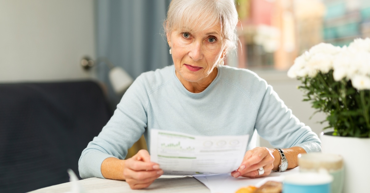 senior woman sitting at table reviewing bills at home