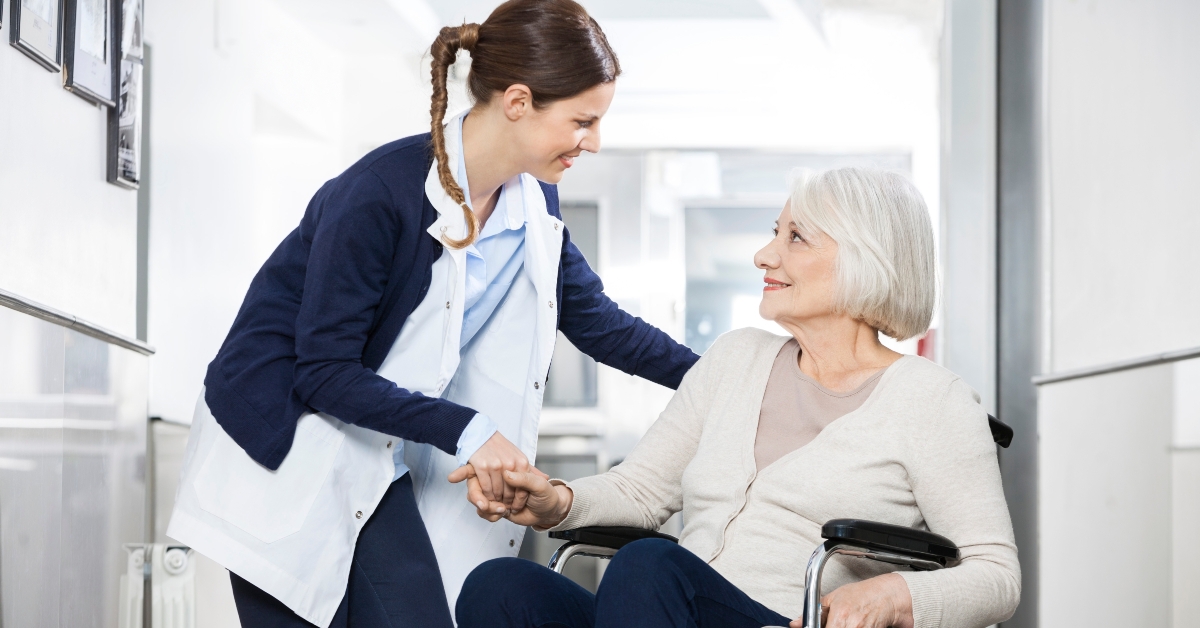 physiotherapist consoling senior woman sitting in wheelchair