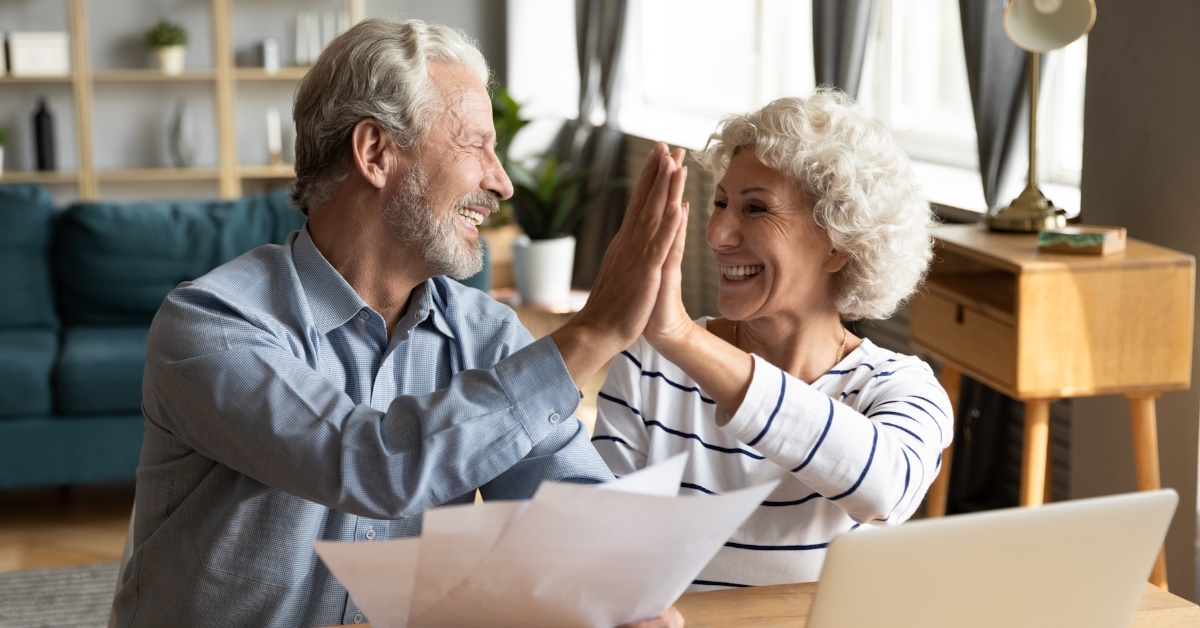 senior couple celebrating after reviewing bills