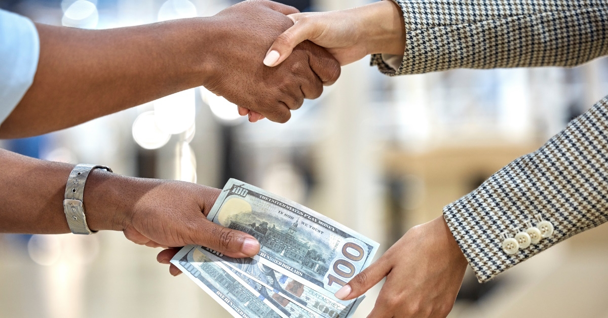 man shaking hand while giving cash