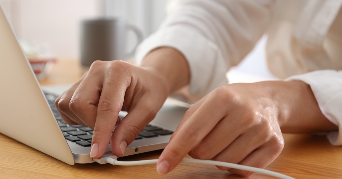 Woman connecting charger to laptop