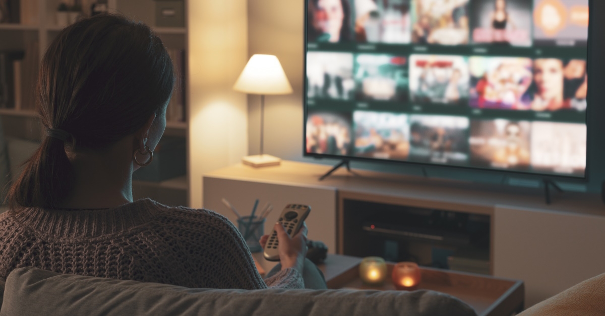 Woman on couch browsing TV shows