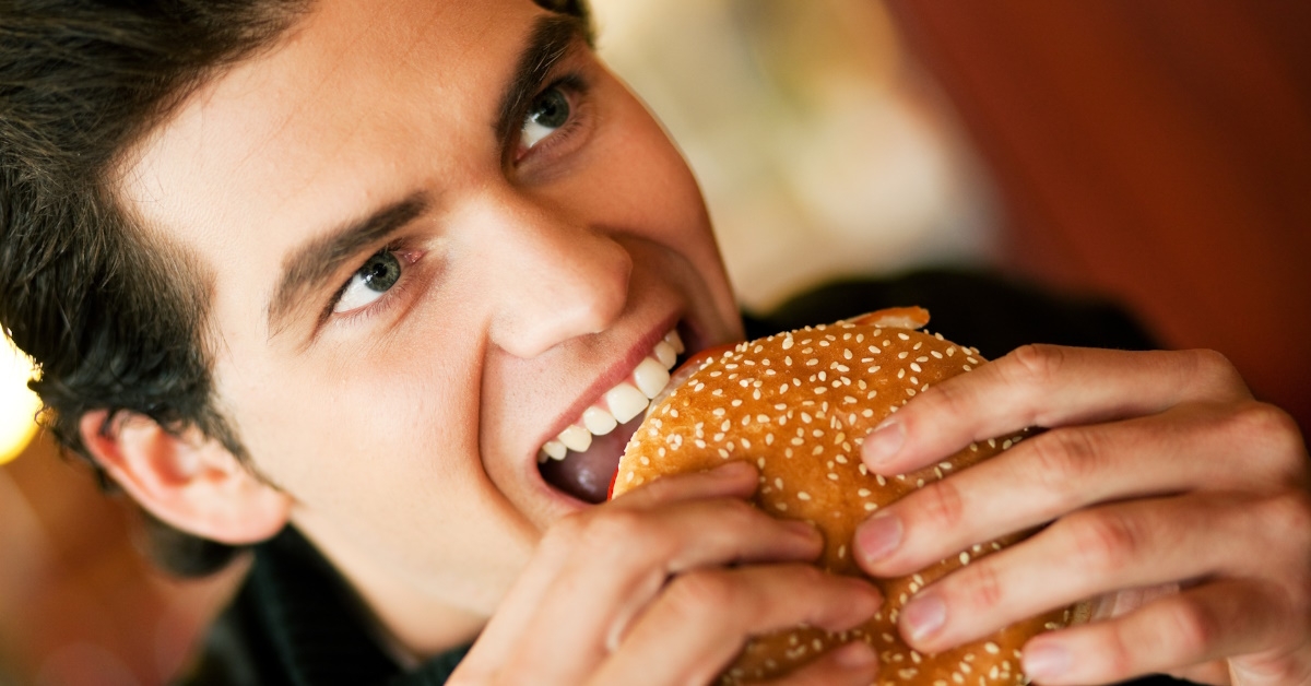 handsome man eating hamburger in restaurent