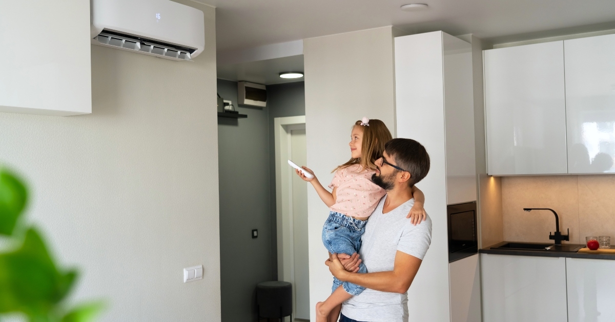 Father with little daughter on hands turn on air conditioner