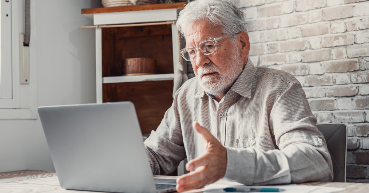Annoyed senior man using laptop