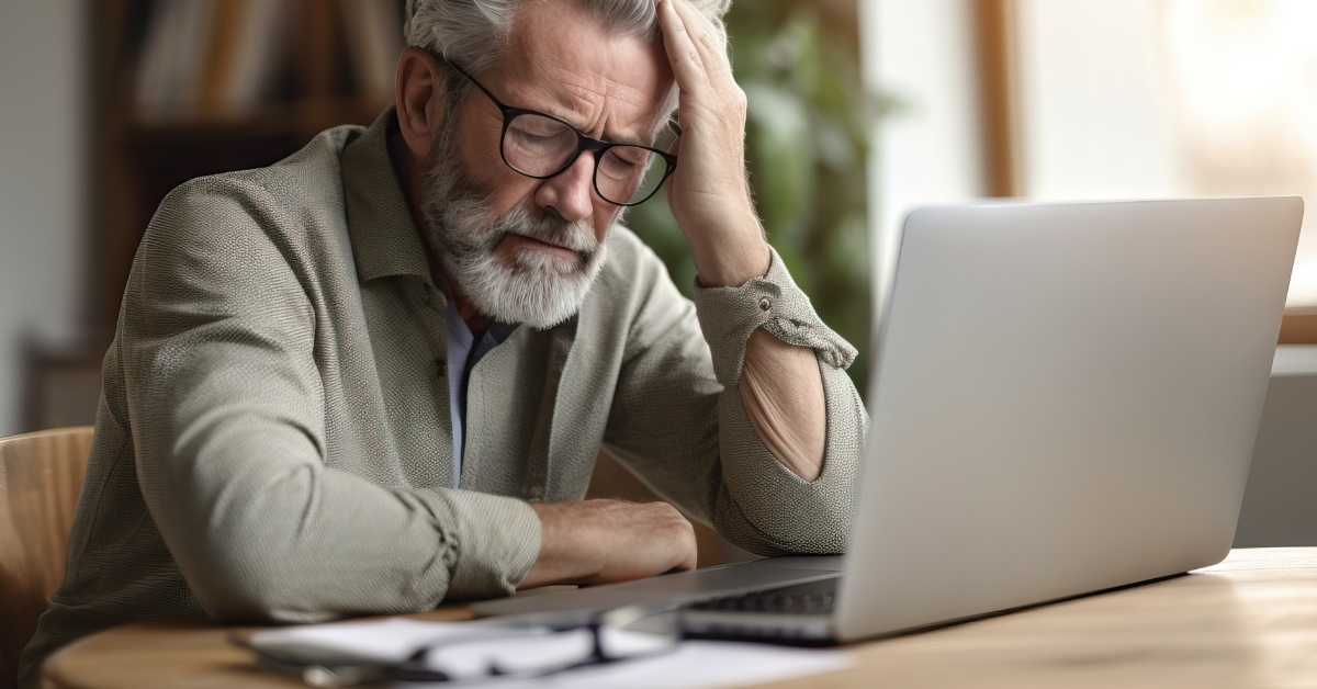 Tired senior man using laptop