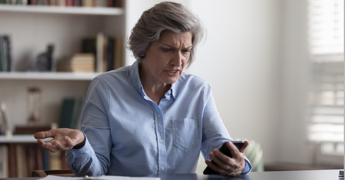 Frustrated senior woman using smartphone