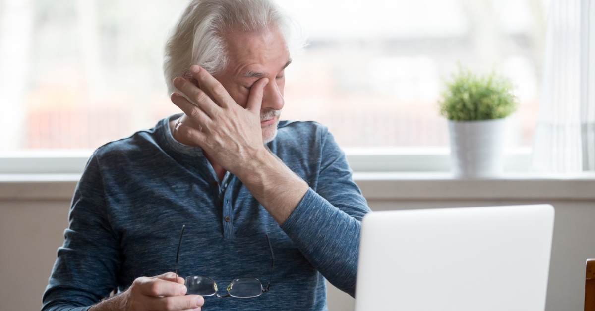 Businessman getting tired while using laptop