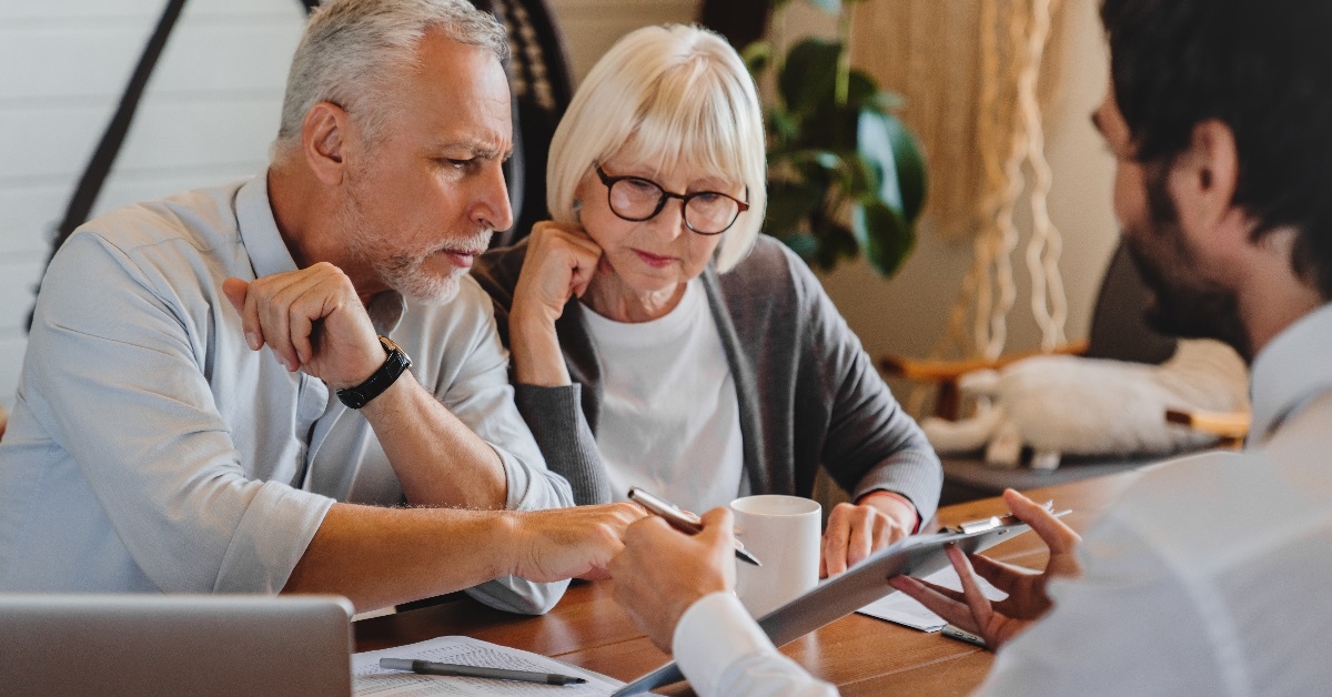 Advisor explaining paperwork to a retired elderly couple.