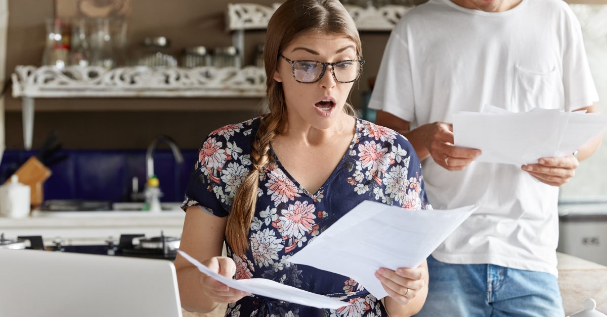 shocked couple reviewing bills at home