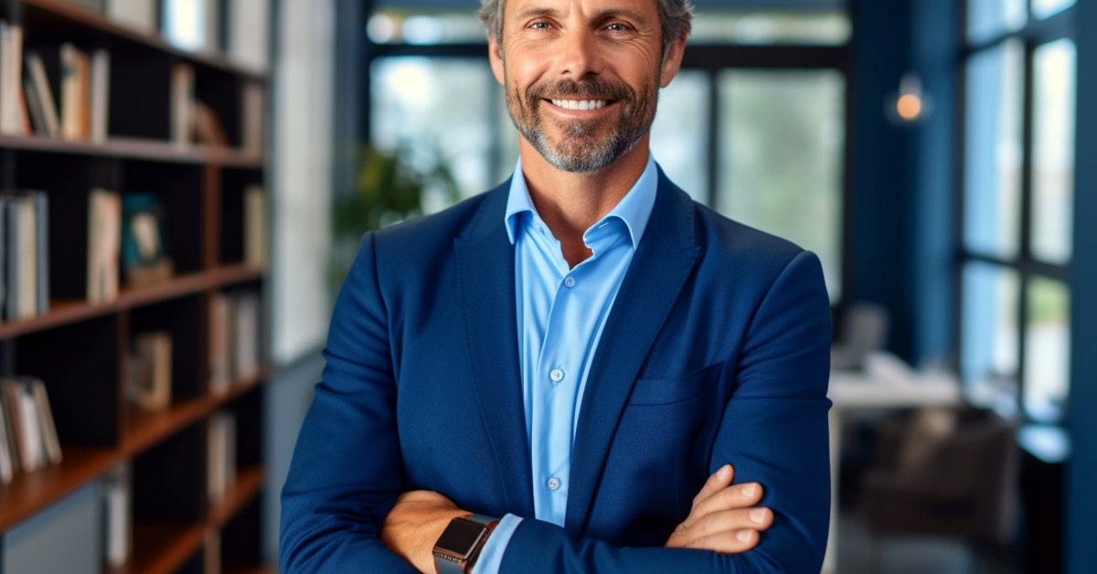 Confident man standing in office with arms crossed.