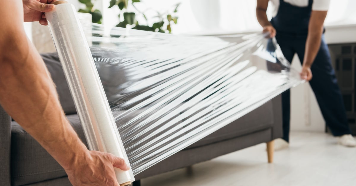 Movers packing sofa with transparent roll