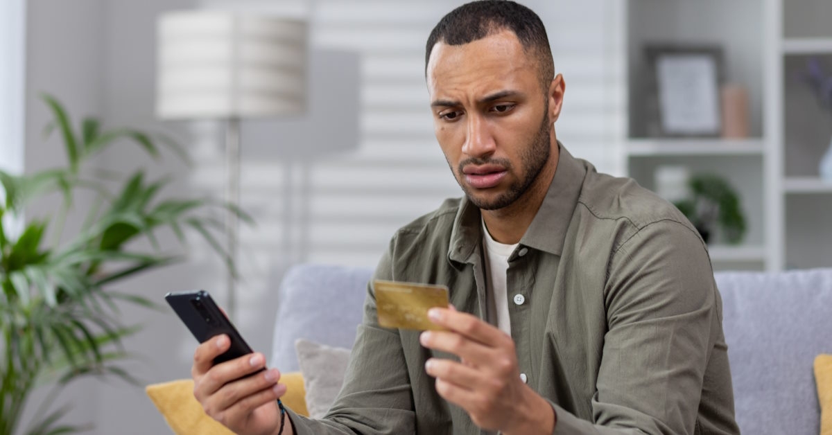 worried man holding card with smartphone