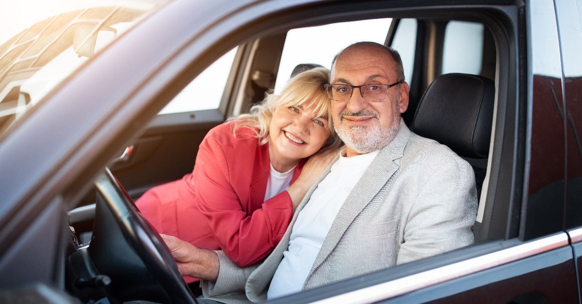 Senior couple sitting in car in happy mood.