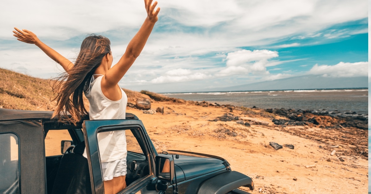 Excited woman on beach in car