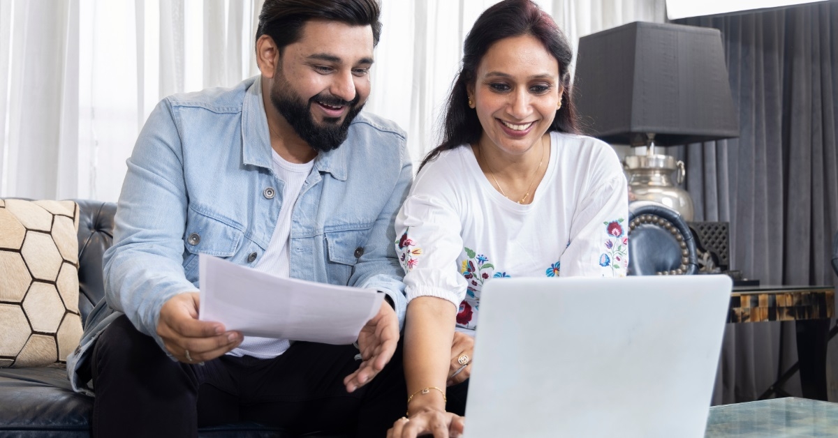 happy couple reviewing bills using laptop