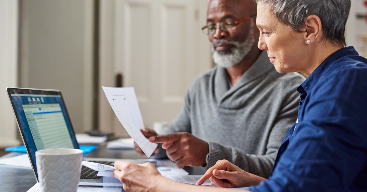 senior couple reviewing bills using laptop