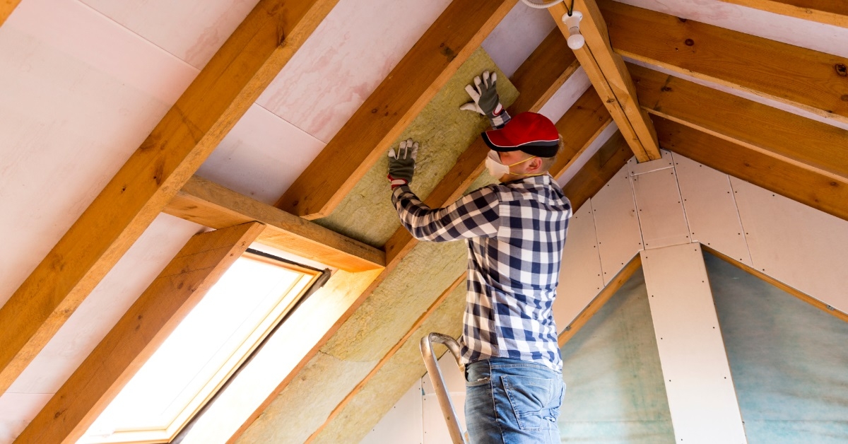 male worker installing insulation on roof