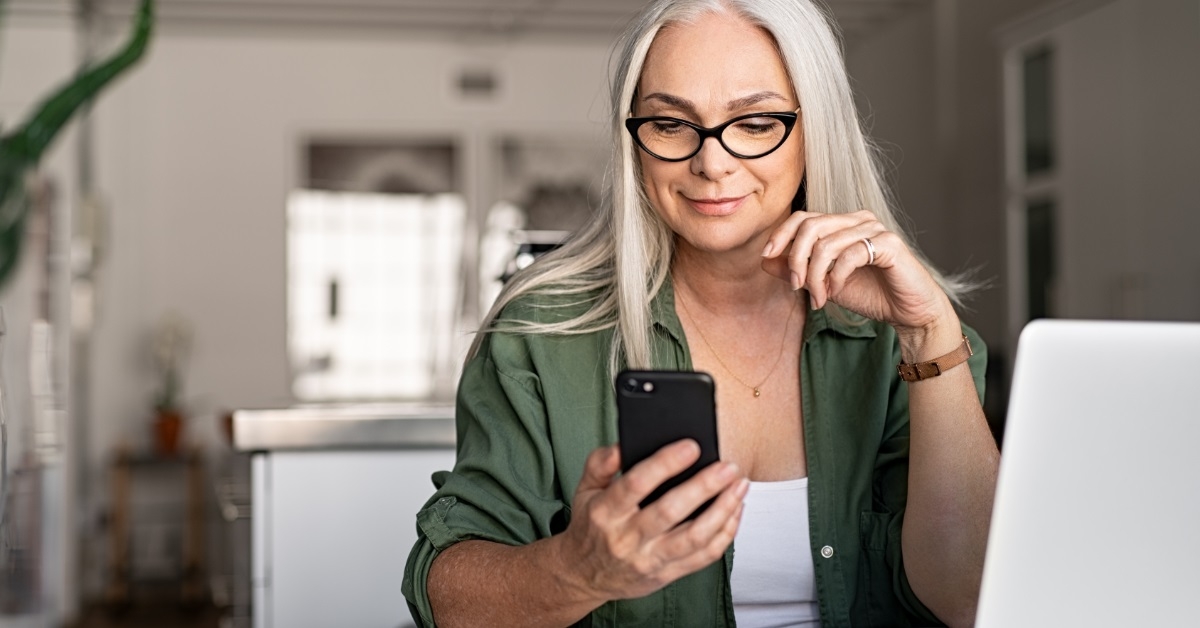 senior woman scrolling smartphone at home