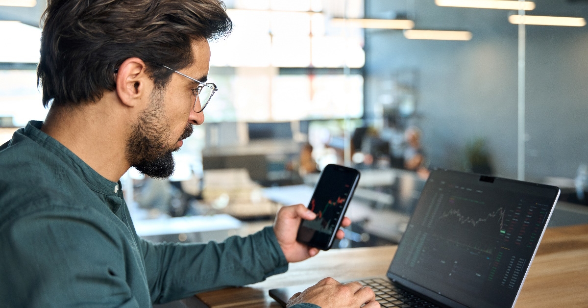 male broker analyzing stocks on smartphone