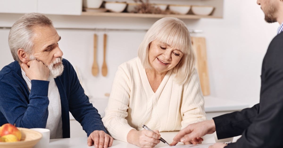senior couple signing documents with advisor