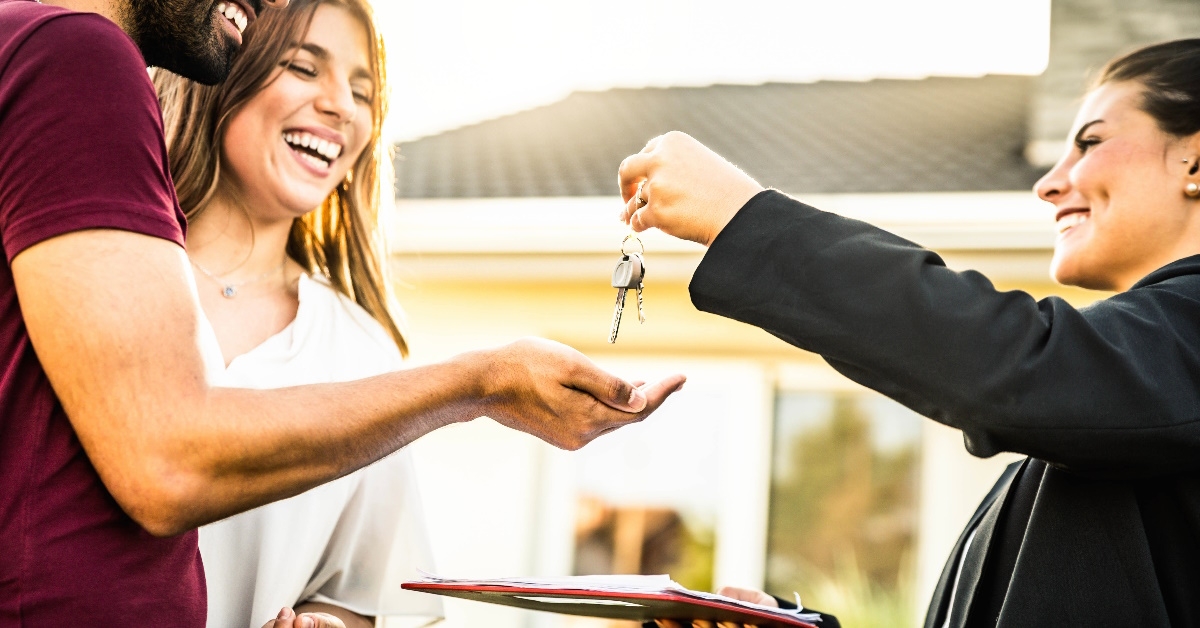 female realtor handing keys to couple