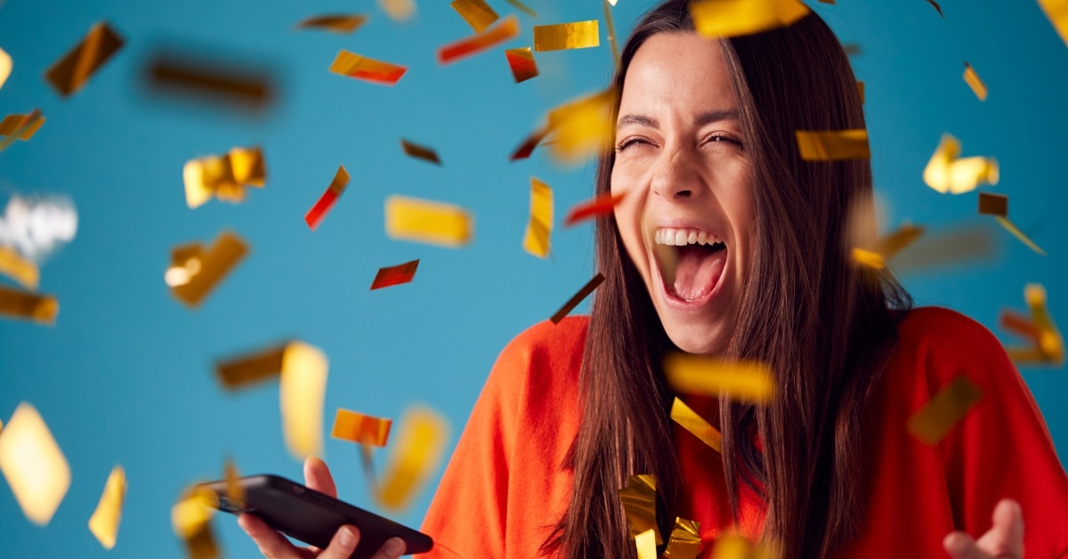 woman holding cellphone celebrating win